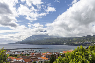 Scenic view of town by sea against sky