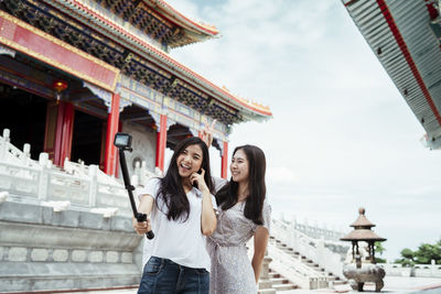 Smiling women vlogging while standing against temple