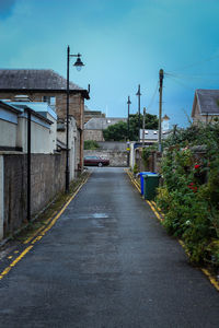 Empty road amidst buildings against sky