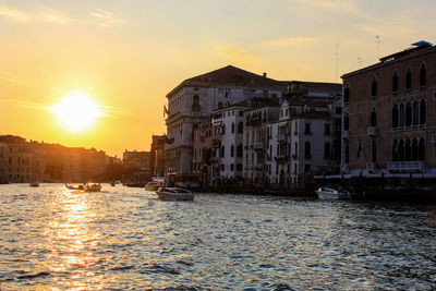 Canal amidst buildings against sky during sunset