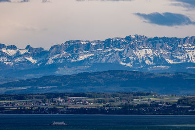 Aerial view of city by mountains against sky