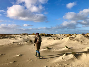 Rear view of woman walking on beach against sky