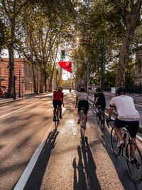 Rear view of people riding bicycles on road