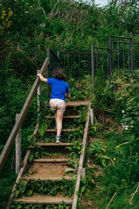 Rear view of girl climbing wooden stairs in a park