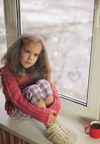 High angle view of girl sitting by window