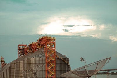 Low angle view of factory against cloudy sky