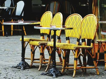 Empty chairs and tables at sidewalk cafe