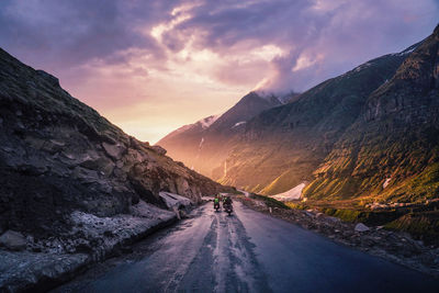 Road amidst mountains against sky during sunset