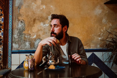 Man eating food while sitting on table in restaurant