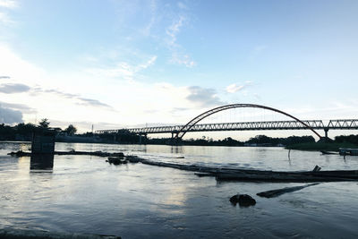 Bridge over river in city against sky