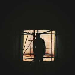 Rear view of silhouette man standing by window