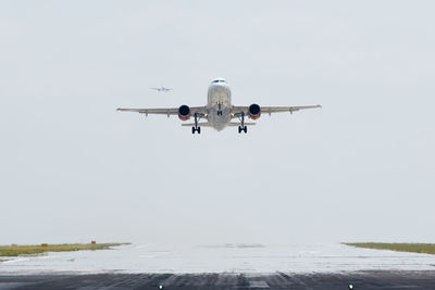 Airplane taking off from airport runway while another airplane is approaching to landing.