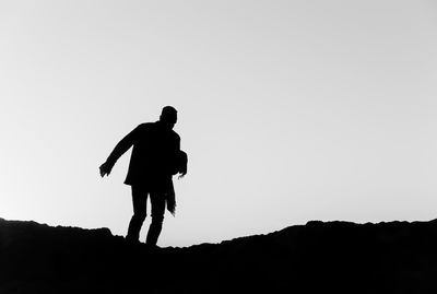 Silhouette man walking on mountain against clear sky