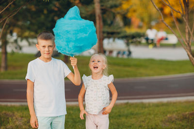 Brother and sister holding cotton candy in park