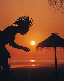 Silhouette person on beach against sky during sunset