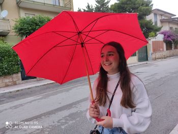 Portrait of a smiling young woman standing in rain