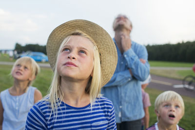 Girl looking up, family on background