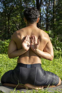 Latin american man doing yoga posture, yoga posture, bee backwards prsthatah brahmara, forest