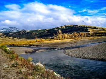 Scenic view of river by mountains against sky