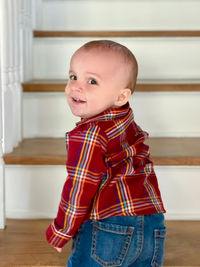 Portrait of cute baby boy standing on steps at home