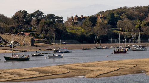 Sailboats moored on river against sky