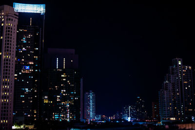 Illuminated buildings in city against sky at night