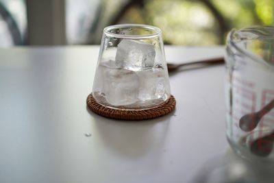 There are some cold ice in the transparent glass on the white table