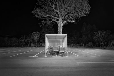 Empty basketball hoop against trees in city at night