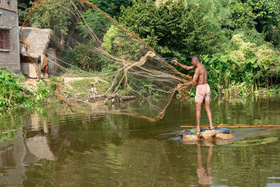 Man standing by fishing net in lake