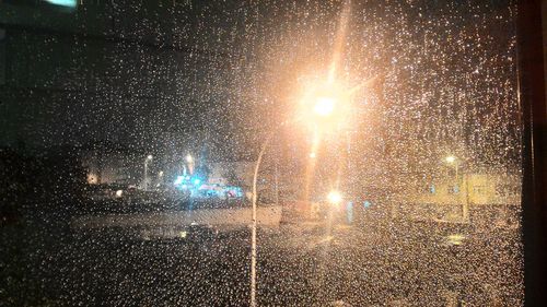 Close-up of wet glass against sky at night