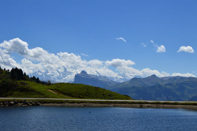 Scenic view of river and mountains against blue sky