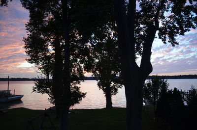 Silhouette trees by lake against sky during sunset