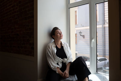 Portrait of young woman sitting on bed at home