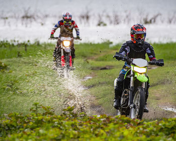 Friends riding dirt-bikes through wetlands near pak chong / thailand