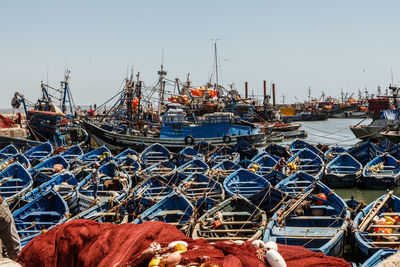 Boats moored at harbor against clear sky