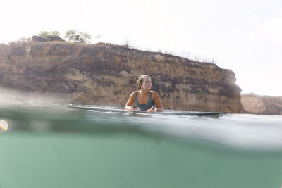 Happy woman sitting on surfboard in sea