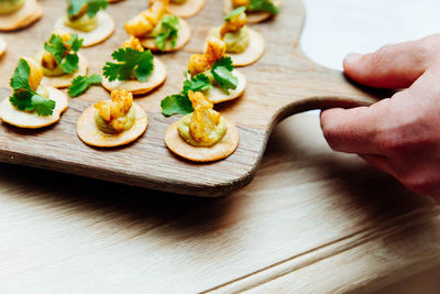 Close-up of hand holding food on cutting board