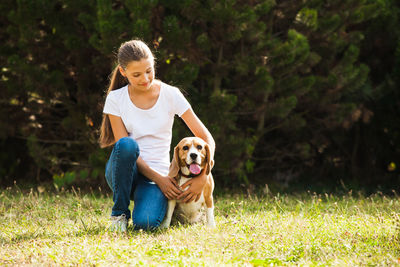 Girl kneeling with dog on grass