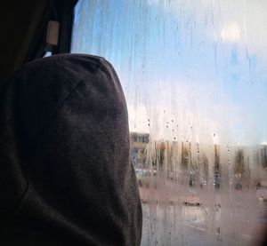 Rear view of man seen through wet window