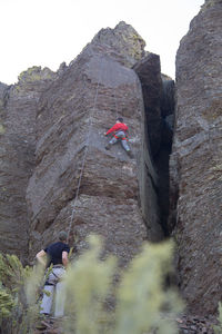 Low angle view of people on cliff against mountain