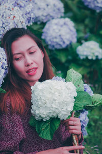 Portrait of a beautiful young woman holding red flowering plants