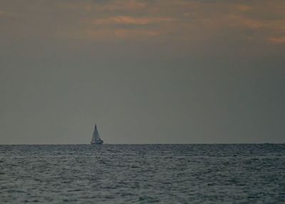 Sailboat sailing on sea against sky during sunset