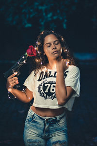 Portrait of a young woman holding ice cream at night