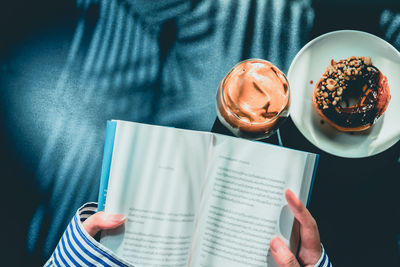 Man holding coffee cup and book on table