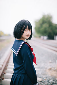 Portrait of woman standing on railroad track