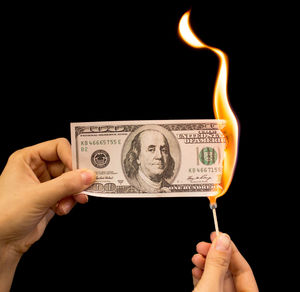 Close-up of hand holding candle against black background
