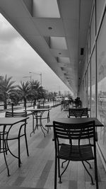 Empty chairs and tables in cafe against buildings