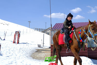 Front view of boy standing on snow covered landscape