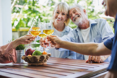 Smiling friends toasting wineglasses while sitting at table