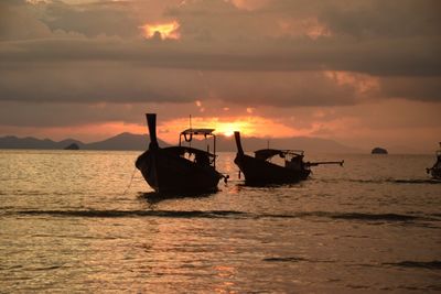 Silhouette boat sailing on sea against sky during sunset